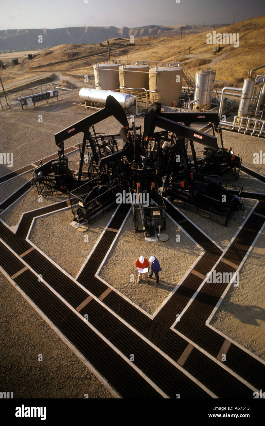 aerial view of technicians discussing data in front of five oil well