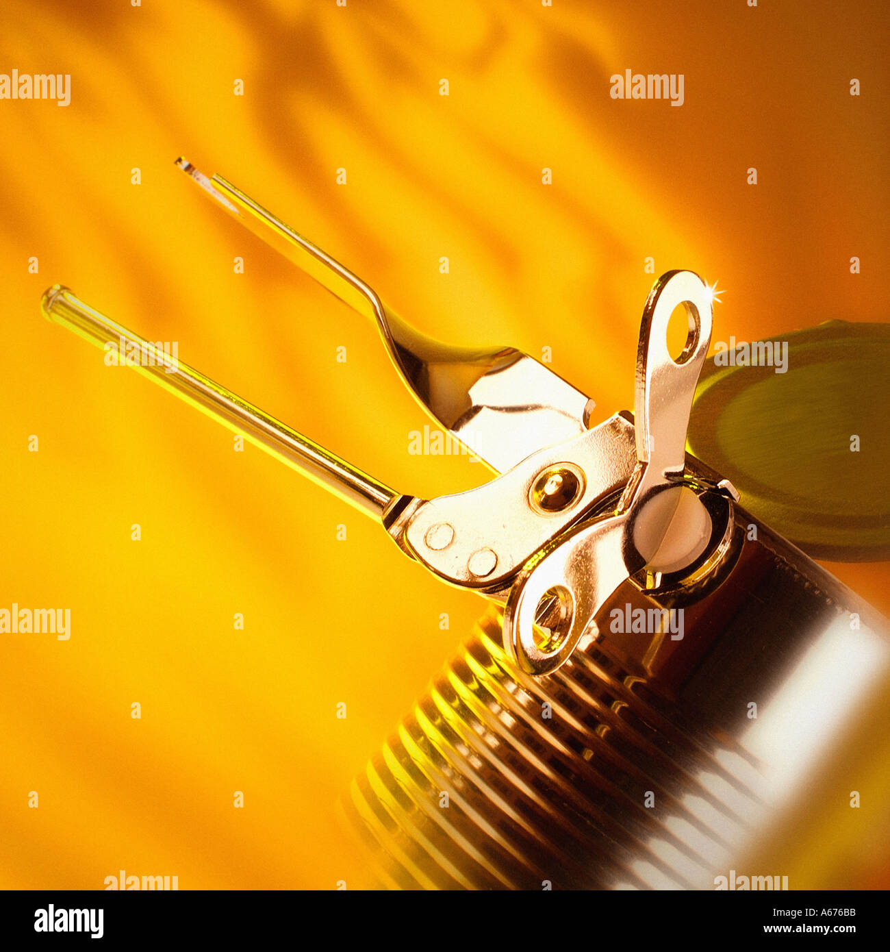 Can opener and can against orange yellow background Stock Photo
