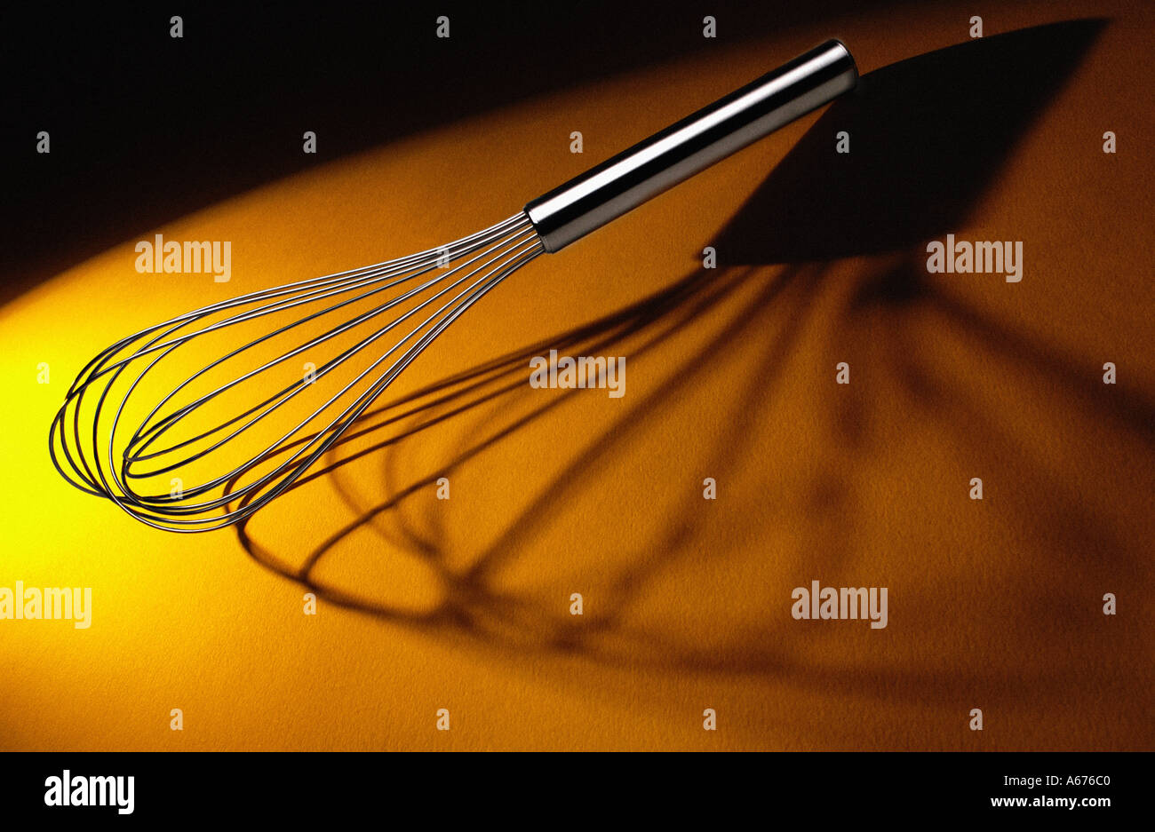 Balloon whisk on yellow orange background Stock Photo