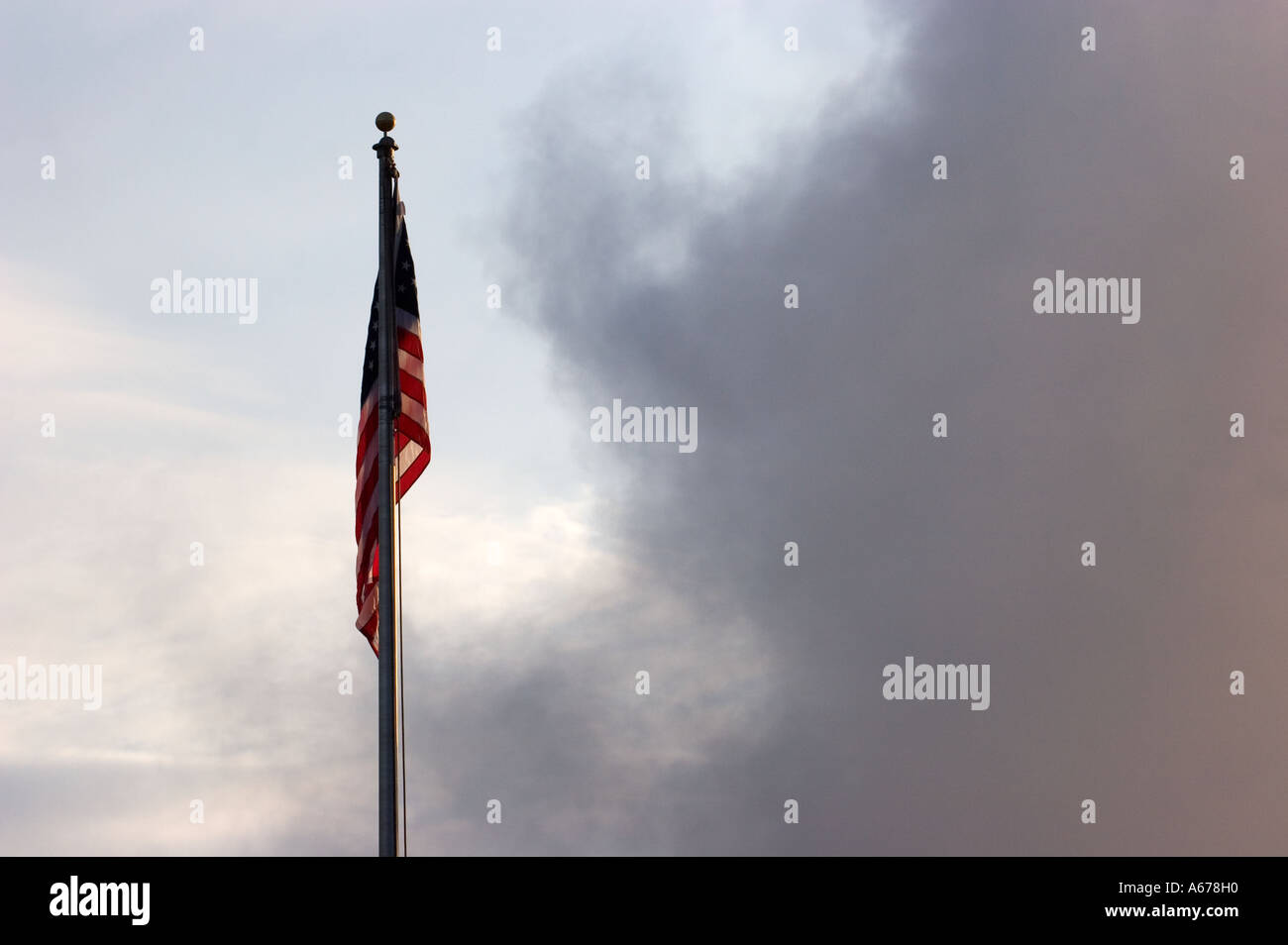 American Flag on pole against clouds and light blue sky Stock Photo
