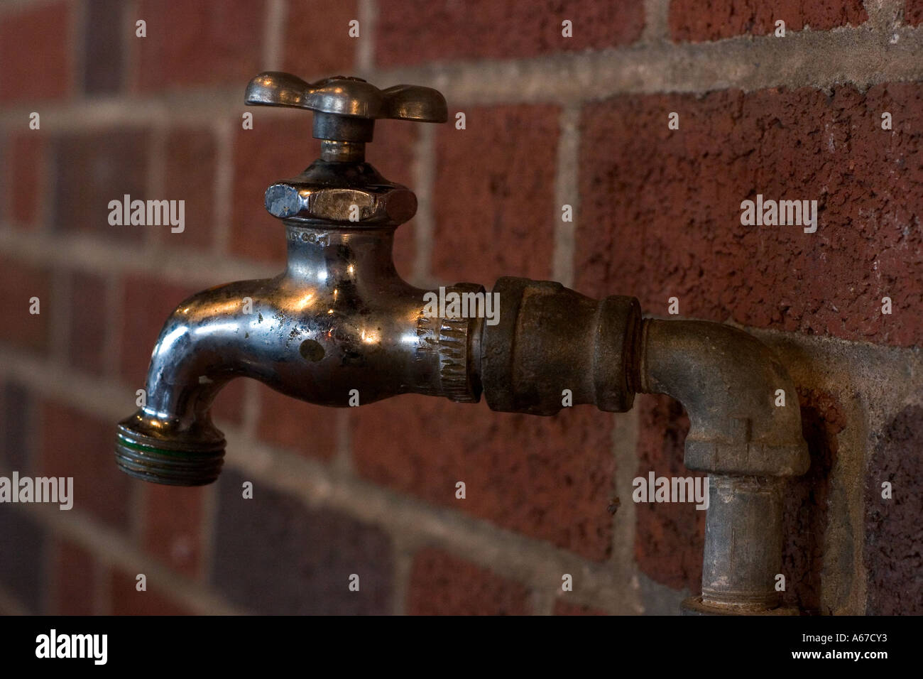 Water spigot against brick wall Stock Photo