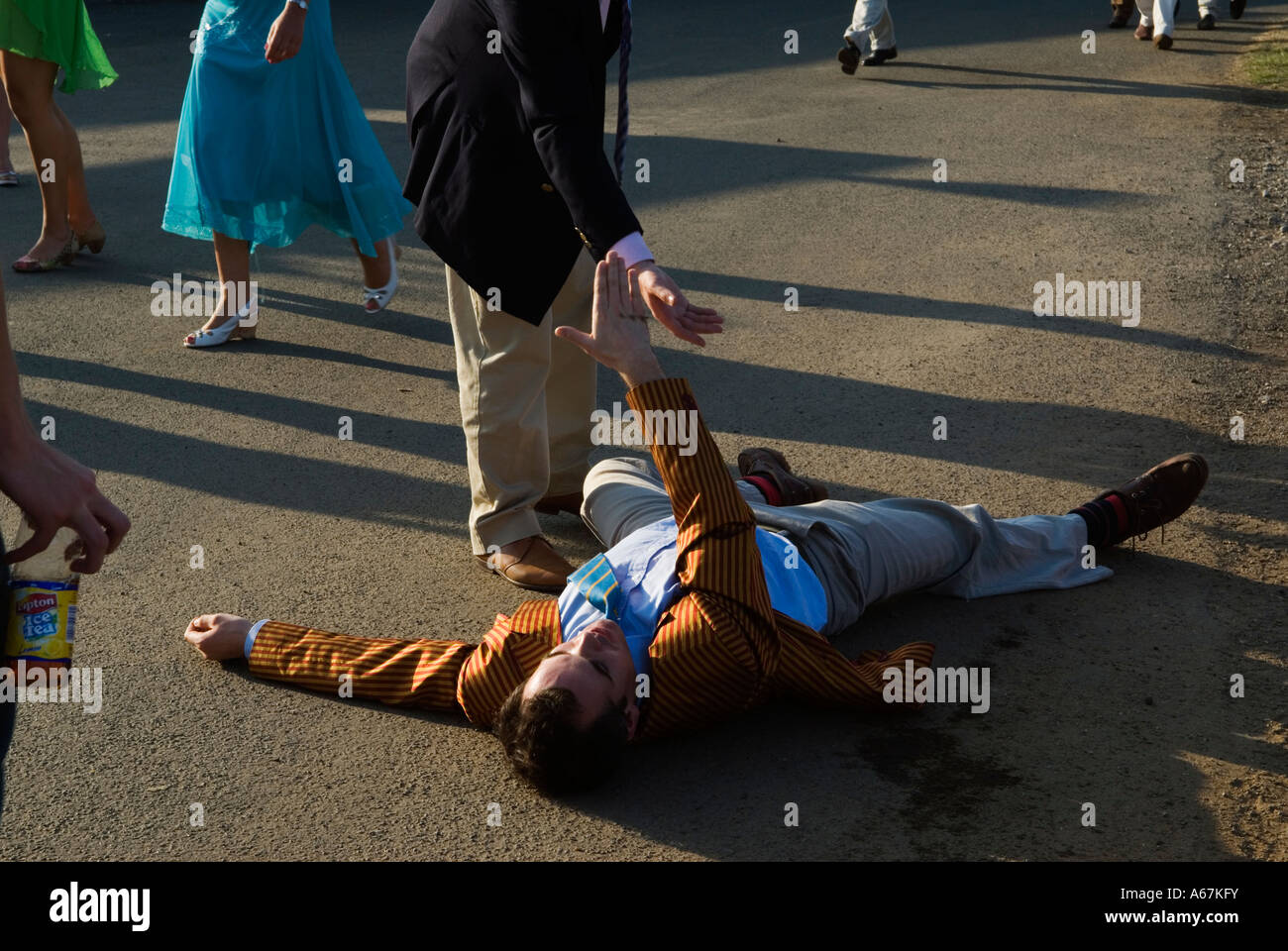 UK, drunk man fallen over, a friend offers a helping hand Henley Royal Regatta. Henley on upon Thames, Oxfordshire 2006 2000s HOMER SYKES Stock Photo