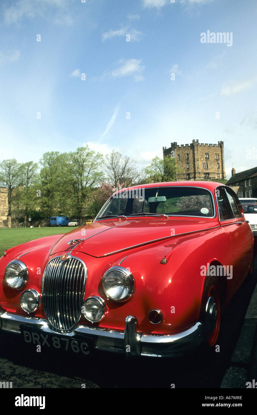 Classic red Jaguar car, similar to one used by Inspector Morse in the TV detective series with stately home in background Stock Photo