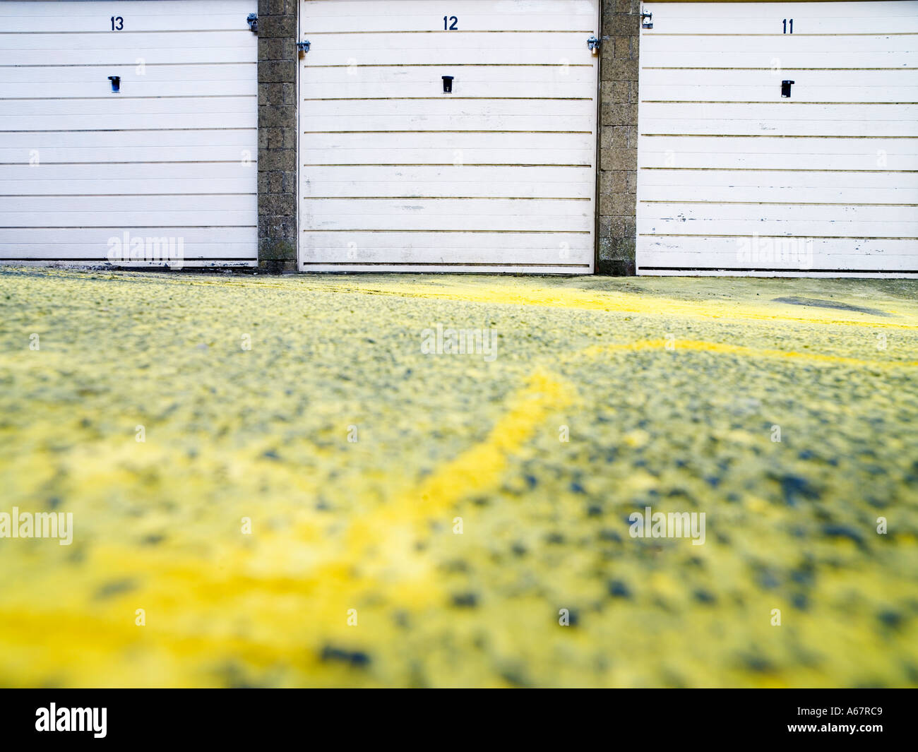 a row of three numbered garage doors yellow paint on gound in front Stock Photo