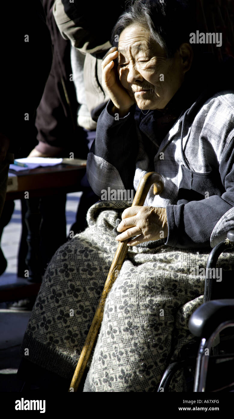 CHINA BEIJING Elderly Chinese woman sitting in her wheel chair listening to opera early in the morning Stock Photo