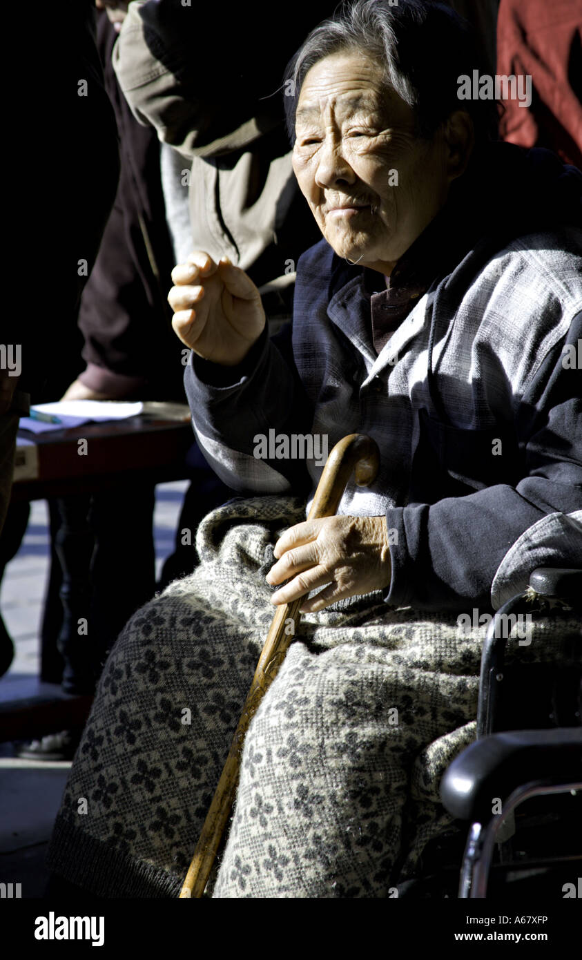 CHINA BEIJING Elderly Chinese woman sitting in her wheel chair listening to opera early in the morning Stock Photo