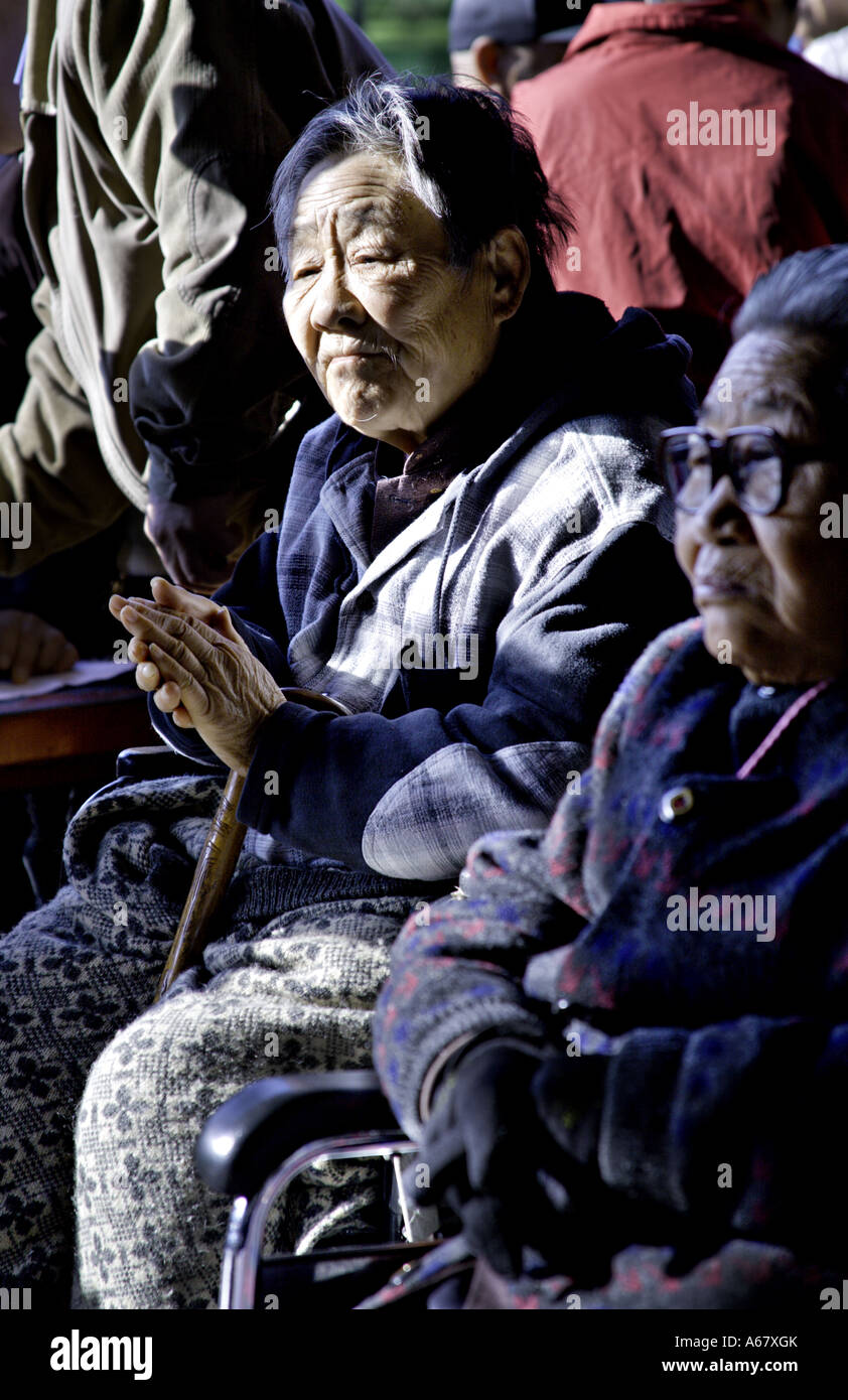 CHINA BEIJING Elderly Chinese woman sitting in her wheelchair in the sunshine claps Stock Photo