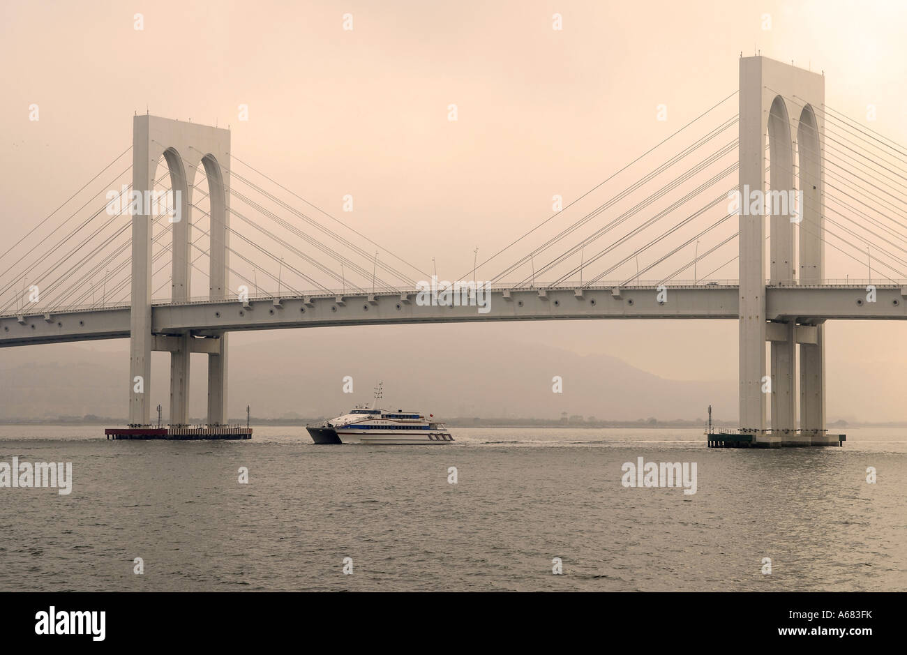 A ferry crossing under the cable-stayed Sai Van bridge which cross the Praia Grande Bay connecting Taipa Island and Macau Peninsula. China Stock Photo
