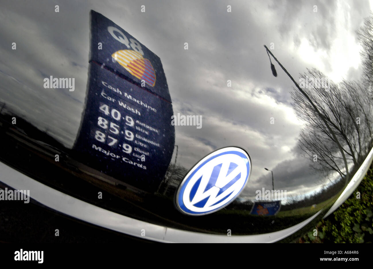 A Q8 gas station sign for petrol at 87.9p reflected in the bonnet of a VW Beetle Stock Photo