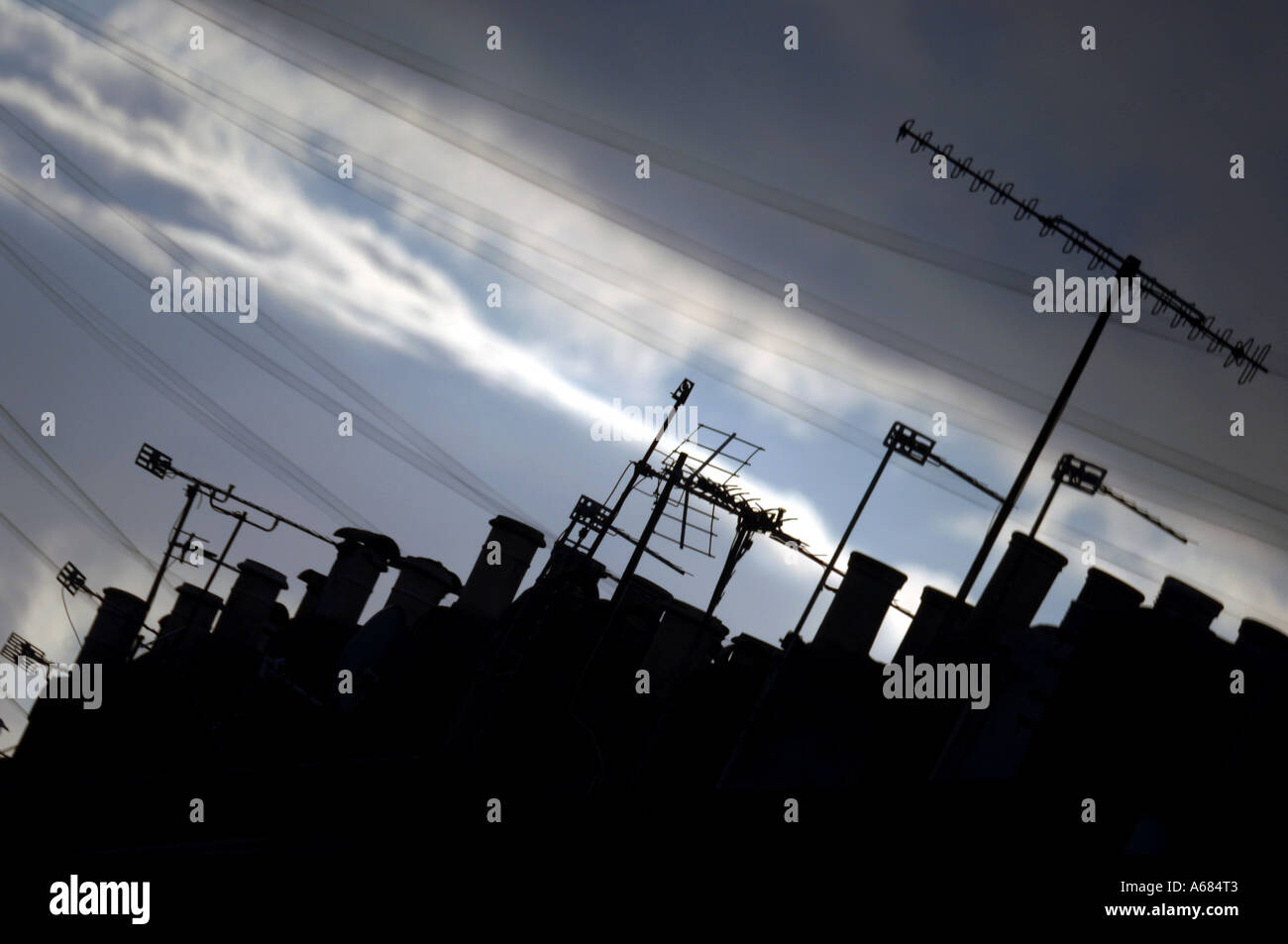 A roofscape with chimney pots and tv aerials at dusk  in a quiet Victorian terraced back street in the city of Brighton and Hove Stock Photo