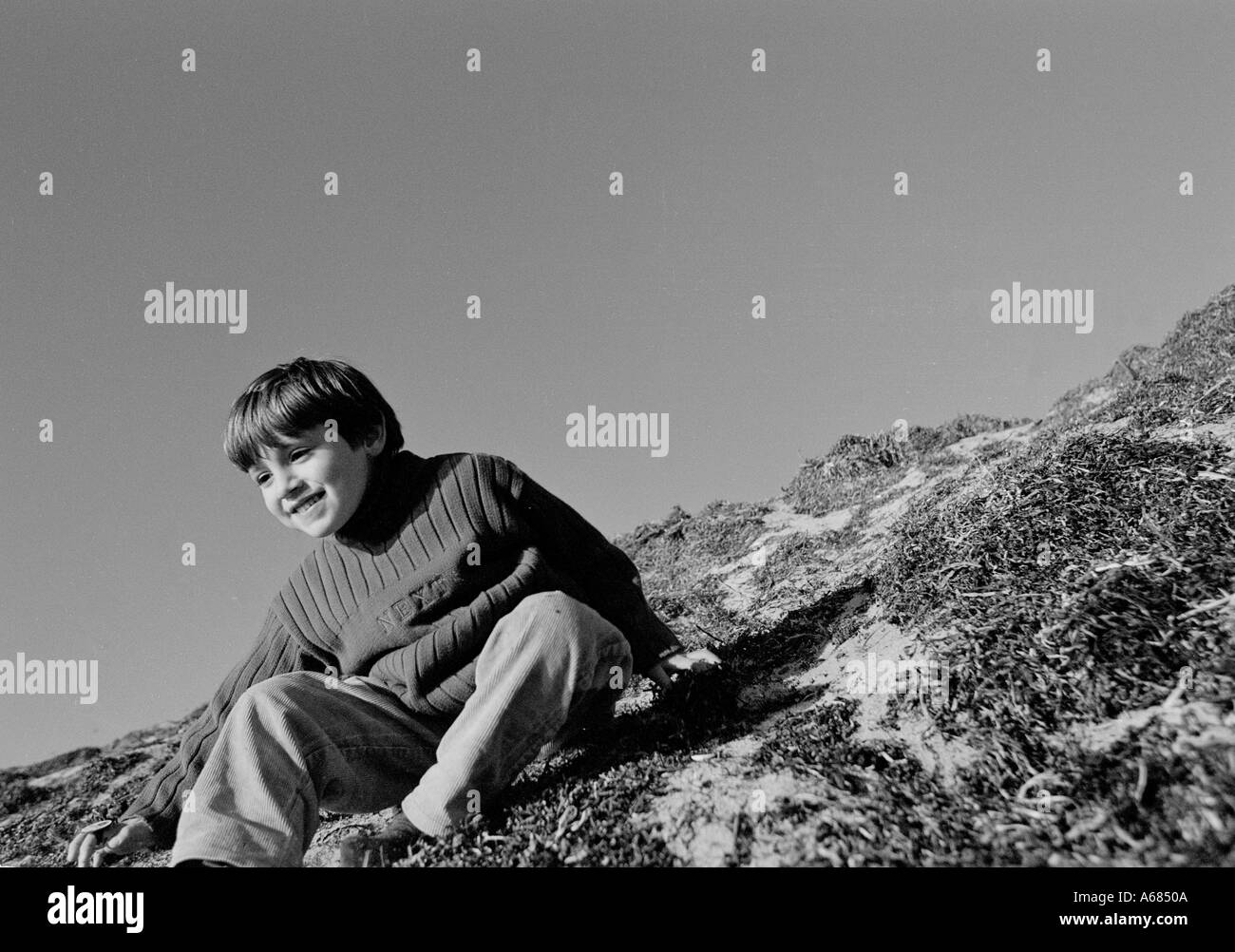 small boy crawling feet first down a steep sandy slope Stock Photo Alamy