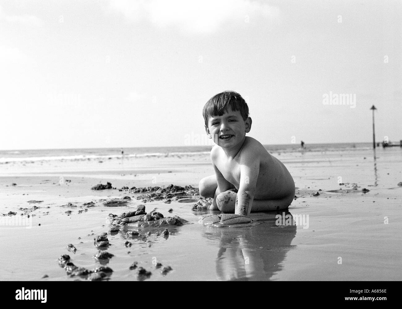 young naked boy on a wet beach playing with sand looking to camera Stock Photo Alamy