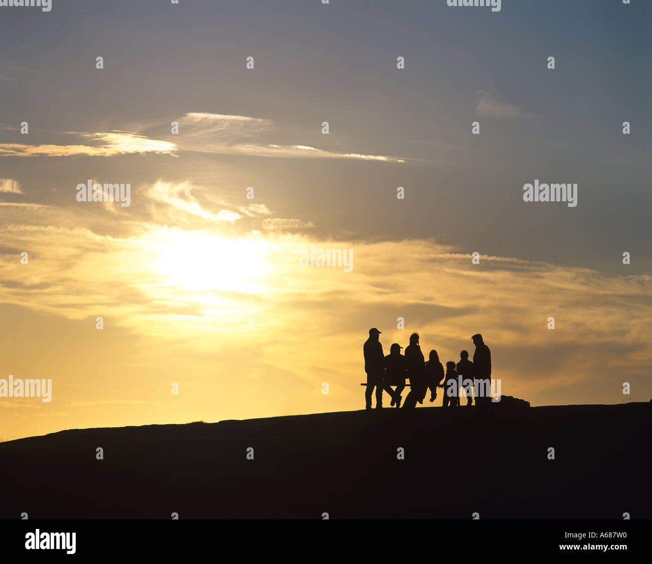 family on bench seat at sunset in Sweden Stock Photo