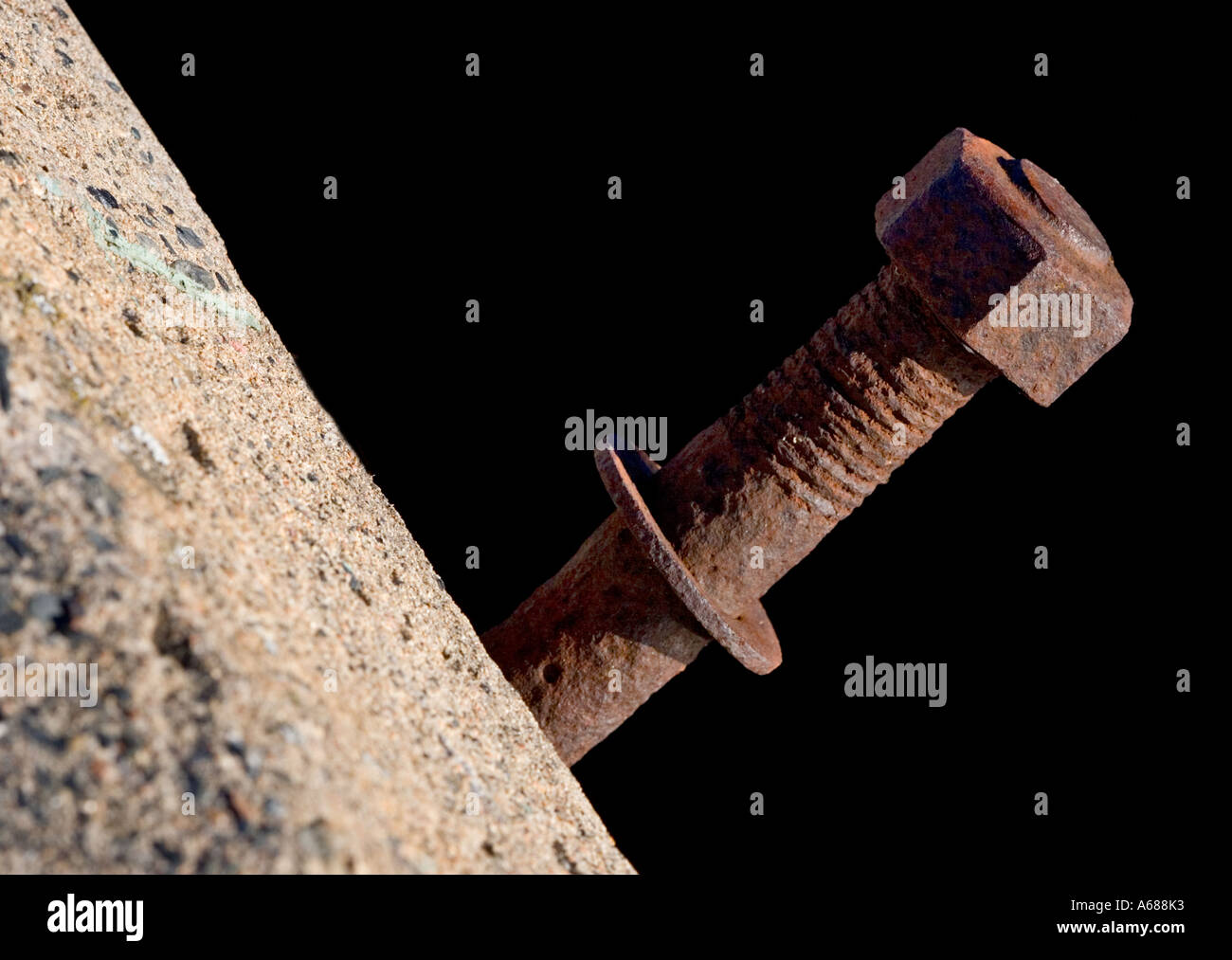 Rusty bolt fastened to concrete and a nut stuck to end of it Stock