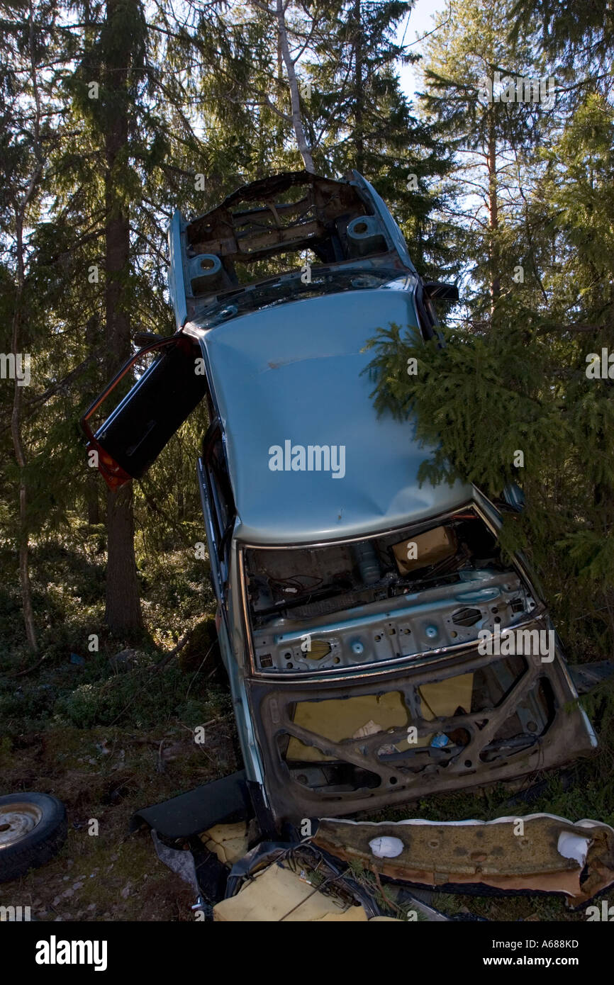 Ripped car frame leaning to tree in forest , Finland Stock Photo