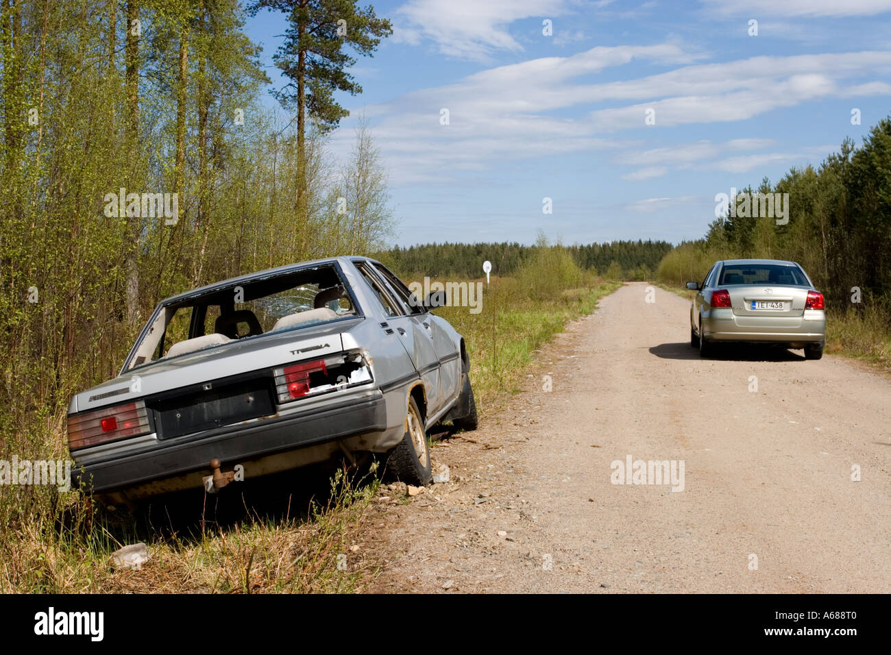 Silver colored abandoned and vandalised sedan at roadside on a side-road , Finland Stock Photo