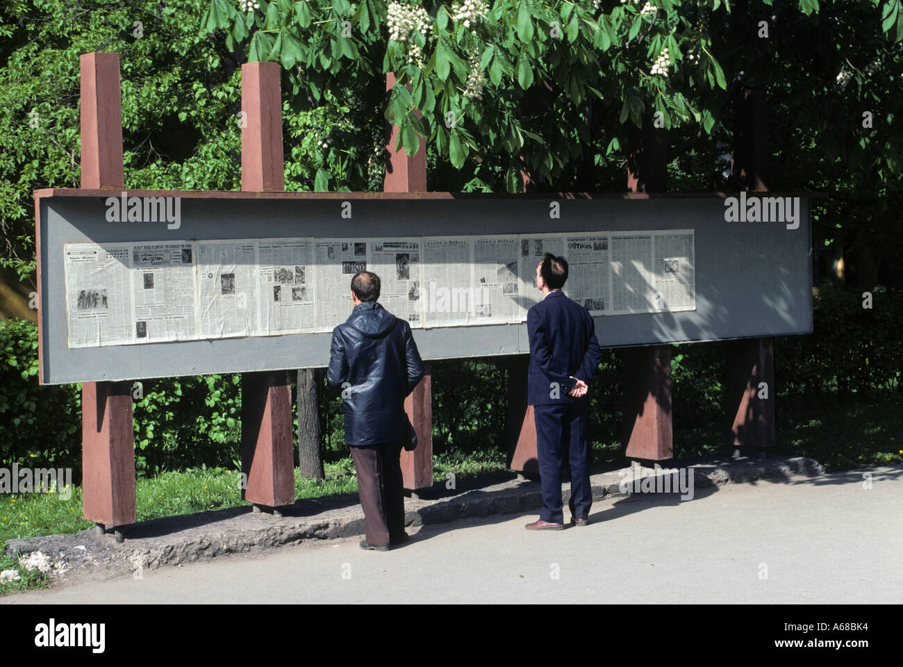 Russian men reading the day's edition of Pravda on a public display board, early 1990s before the collapse of the Soviet Union Stock Photo