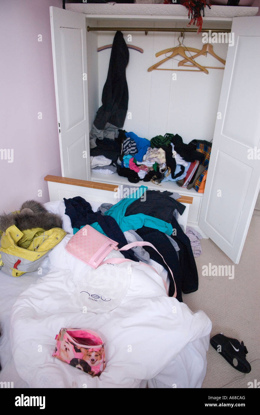 Teenagers untidy messy bedroom UK. Teen girl, fifteen years old bed room and unmade bed and cupboard HOMER SYKES Stock Photo