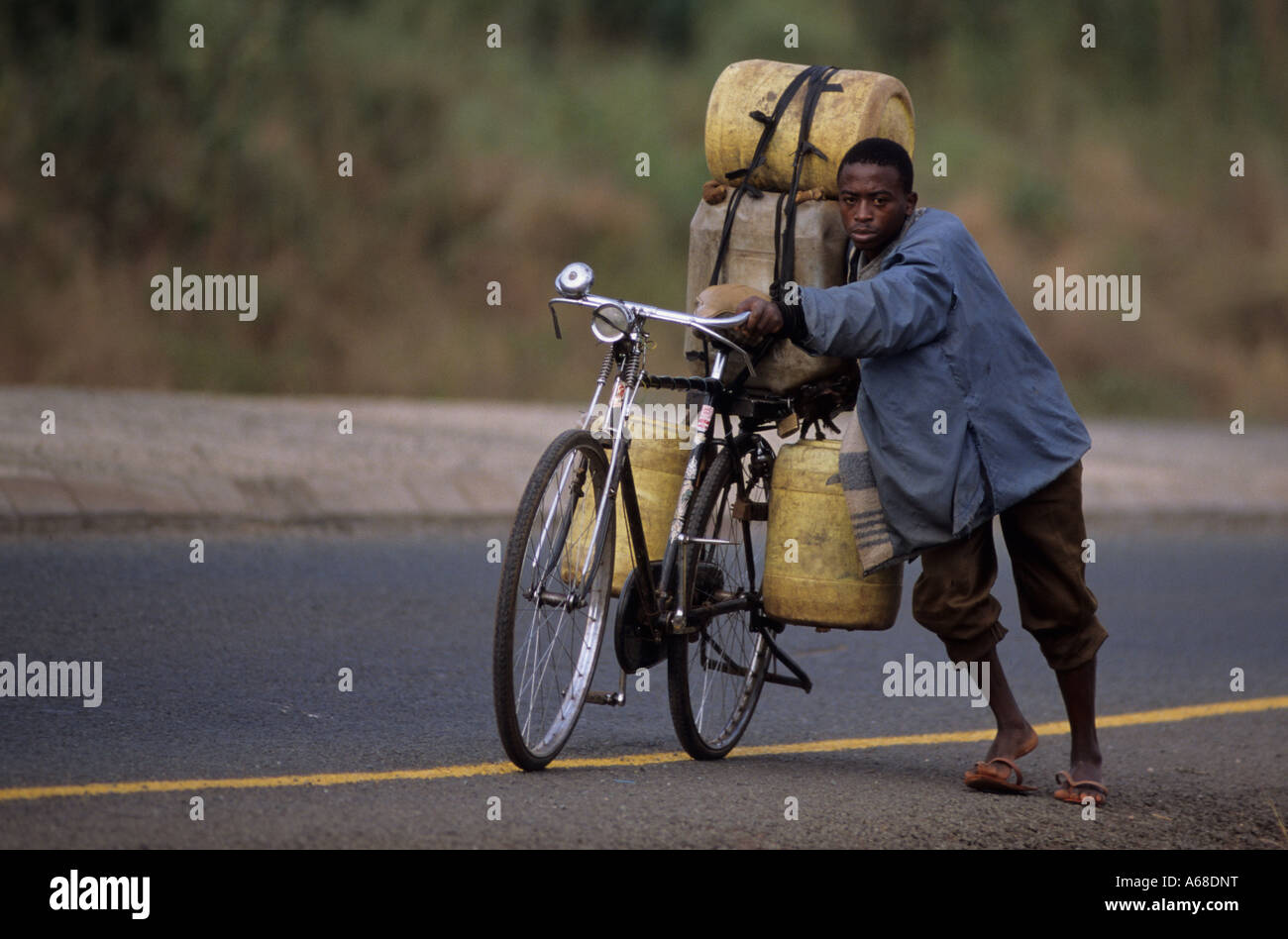 Water seller pushes a bike loaded with drinking water containers in Himo Kilimanjaro Tanzania Stock Photo