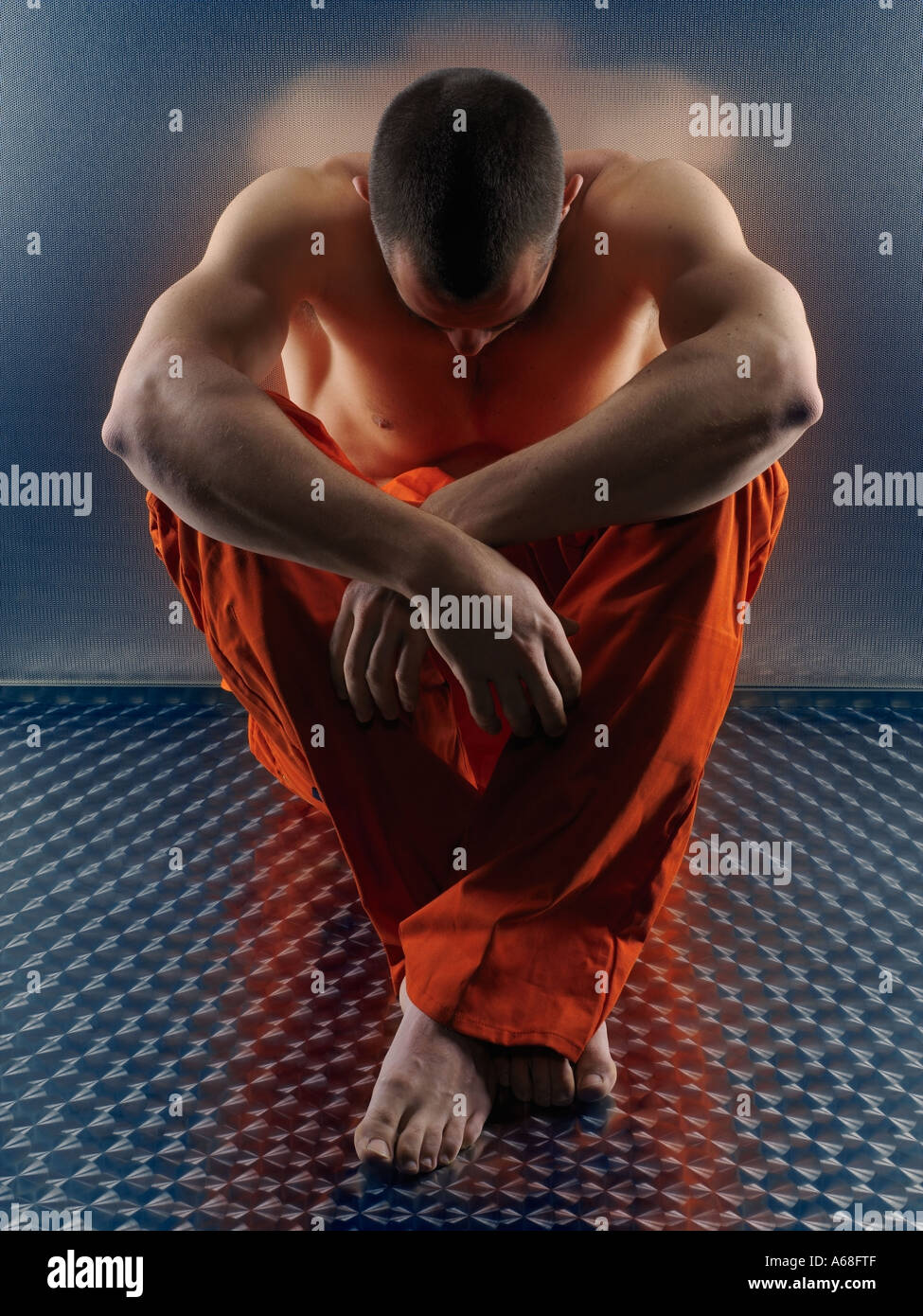 Bare chested man sitting on the floor and wearing orange martial arts