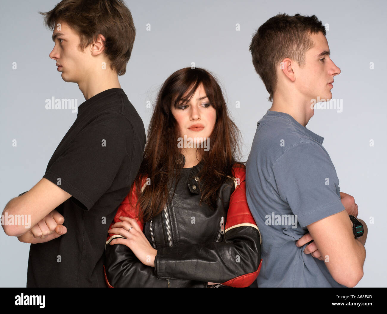 Young woman standing in the middle of two young men with folded arms Stock Photo