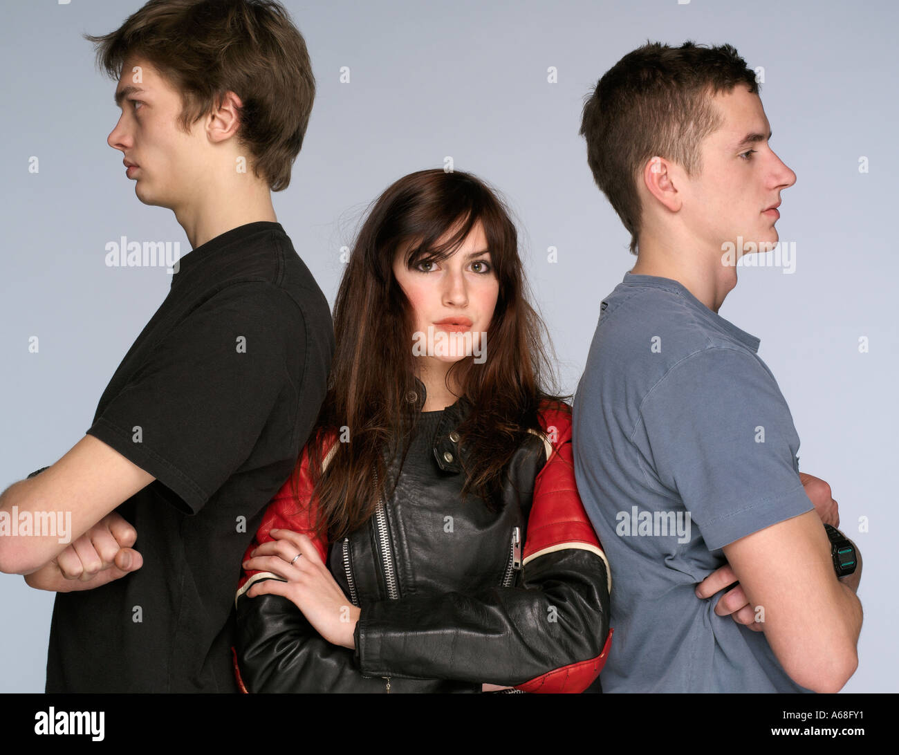 Young woman standing in the middle of two young men with folded arms Stock Photo