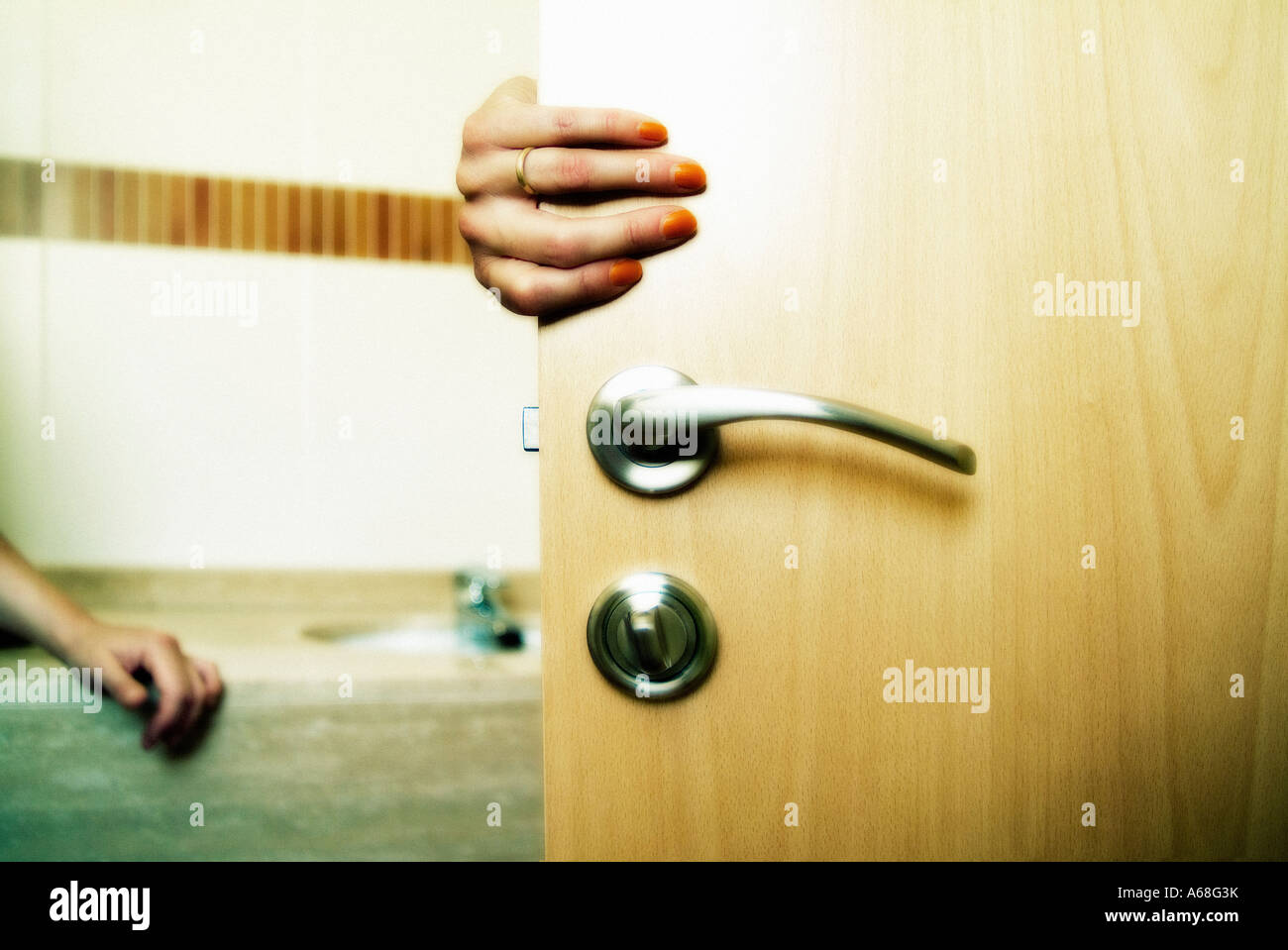 Hand opening a bathroom's door and someone waiting inside Stock Photo
