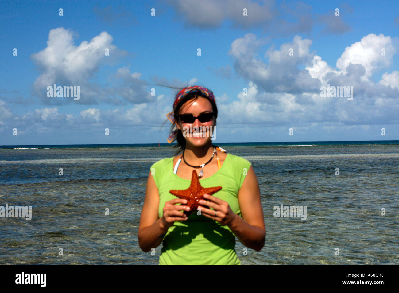 British Virgin Islands Caribbean Woman in colorful clothes smiles while holding a red star fish Stock Photo