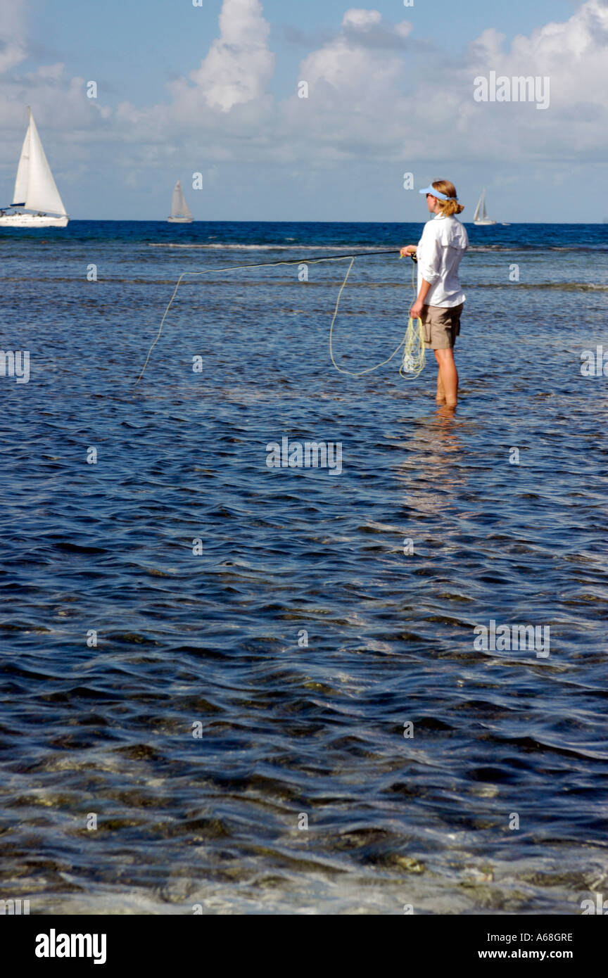 British Virgin Islands Caribbean Woman salt water fly fishing in the North Sound with a sail boat in the background Stock Photo