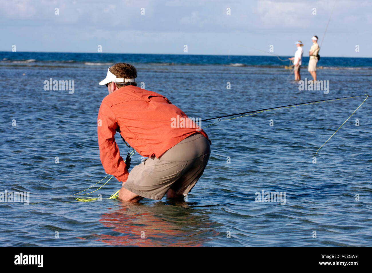 British Virgin Islands Caribbean Man crouches to see bone fish while salt water fly fishing the Virgin Gorda Sound. Stock Photo