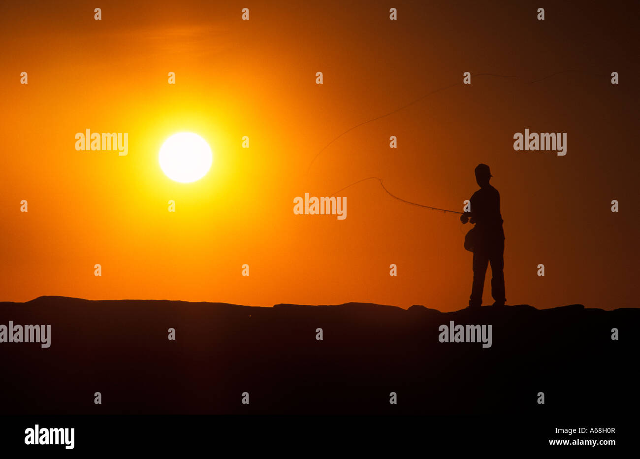 Boy fishing from a jetty at sunset Menemsha Marthas Vineyard Stock Photo
