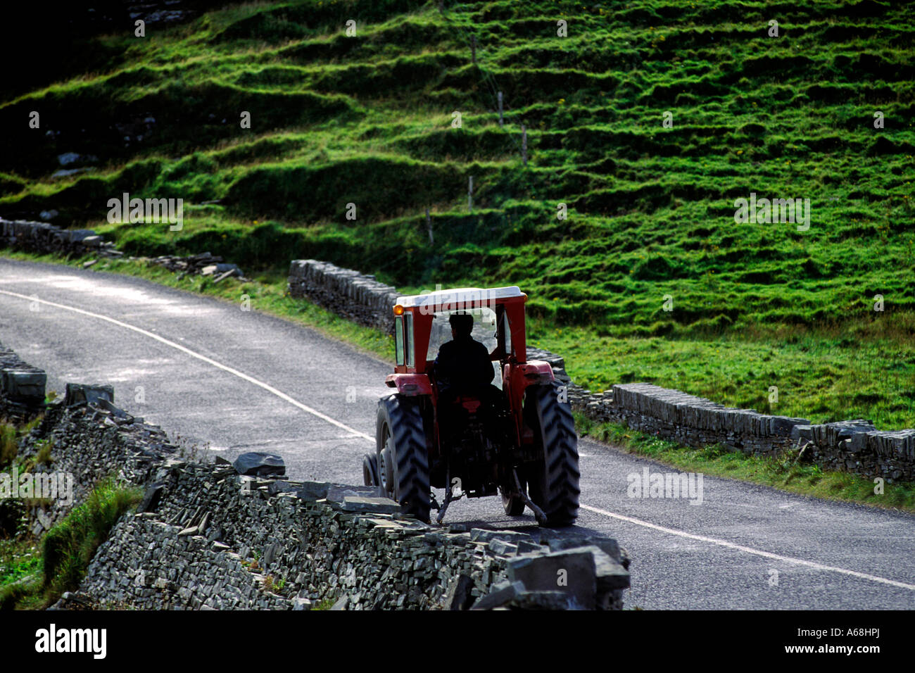 Farmer driving a tractor on a narrow country road Ireland Stock Photo