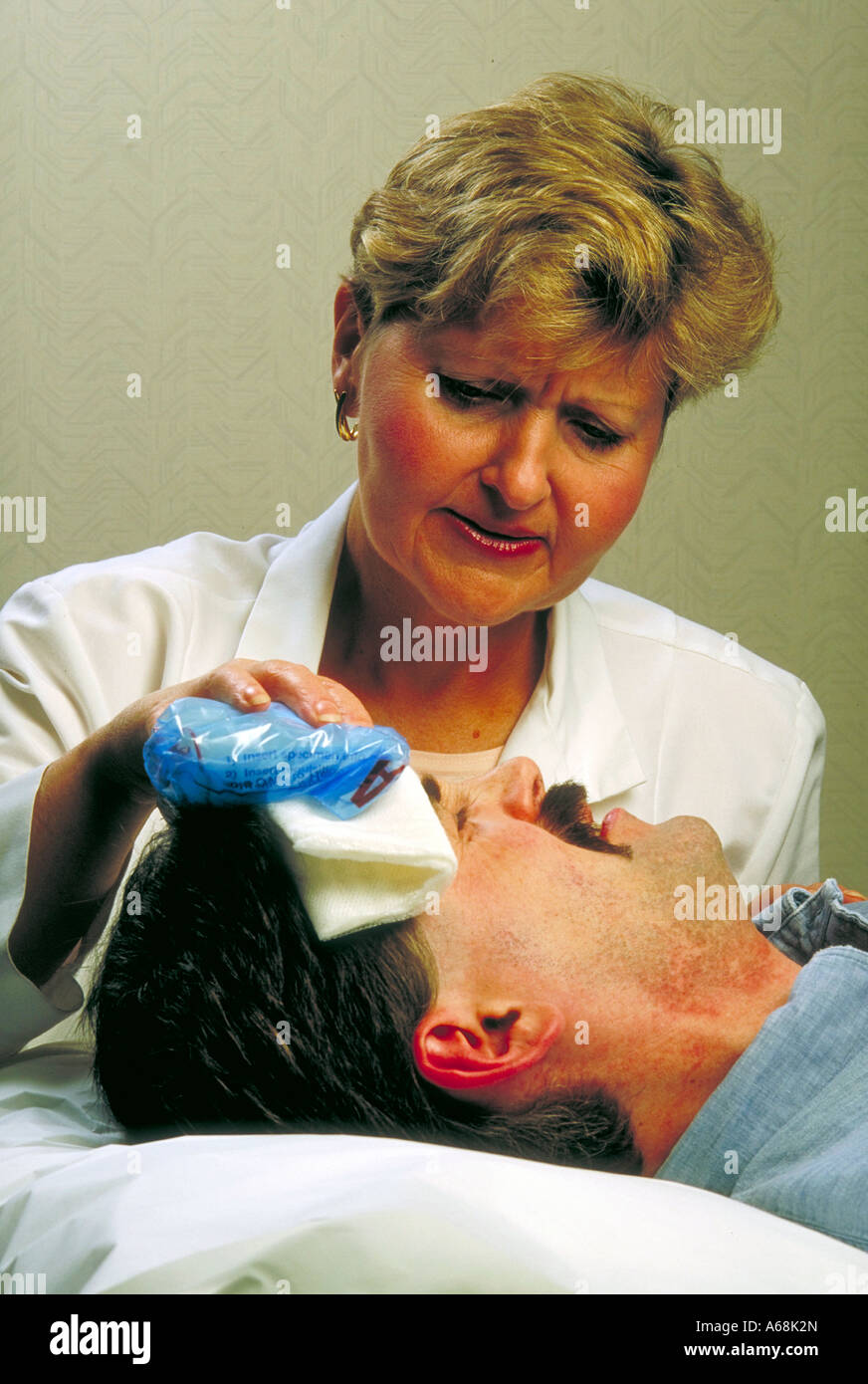 Nurse applies cold compress to head injury patient Stock Photo