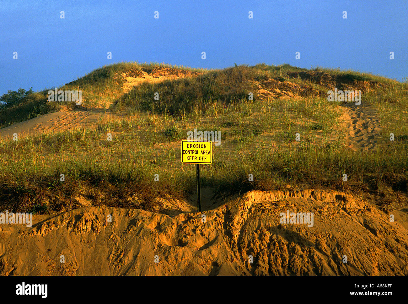 Cliff and sand dunes along the shoreline shows signs of continued erosion Warning sign Stock Photo