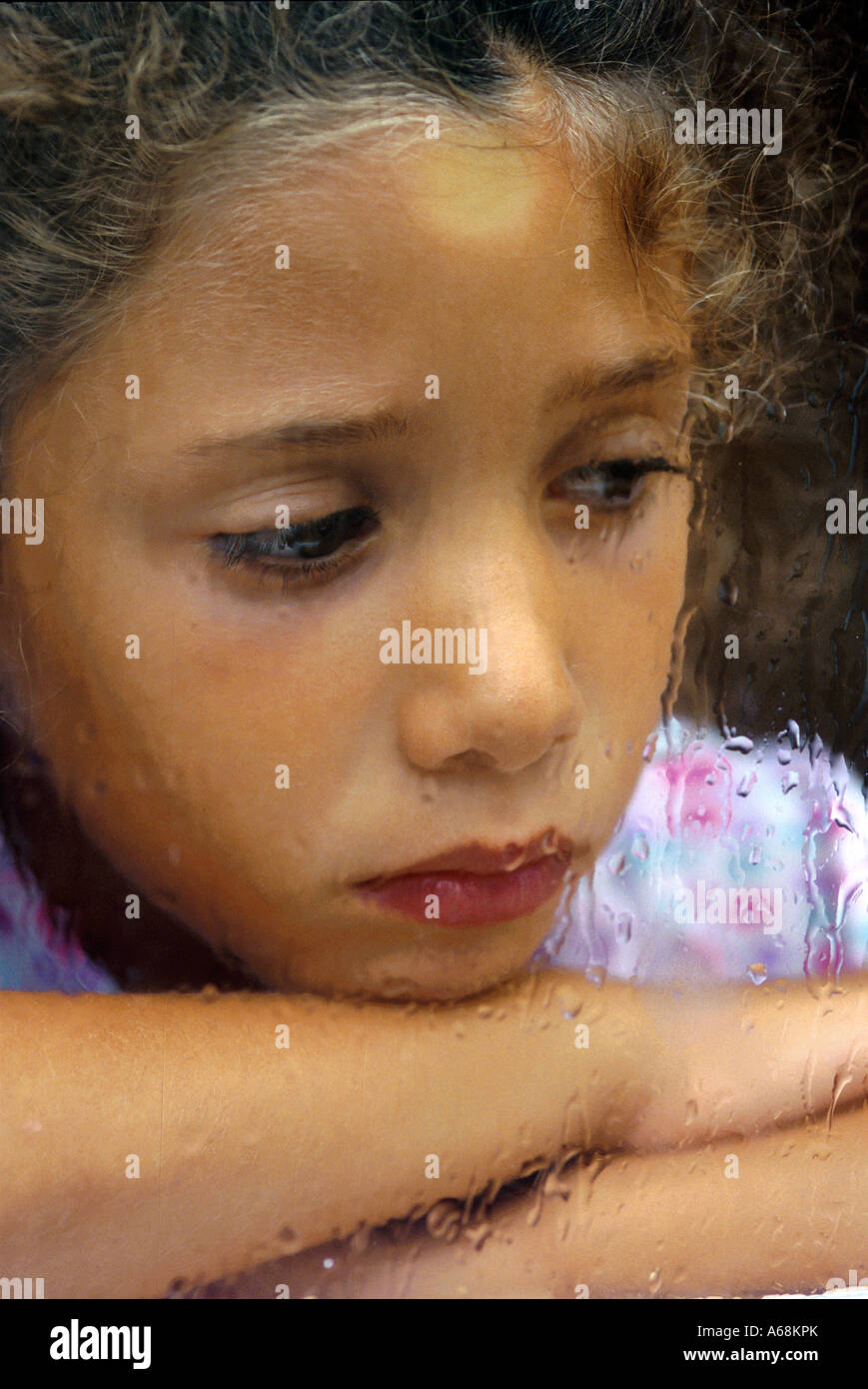 Sad girl looking out the rain streaked window Stock Photo