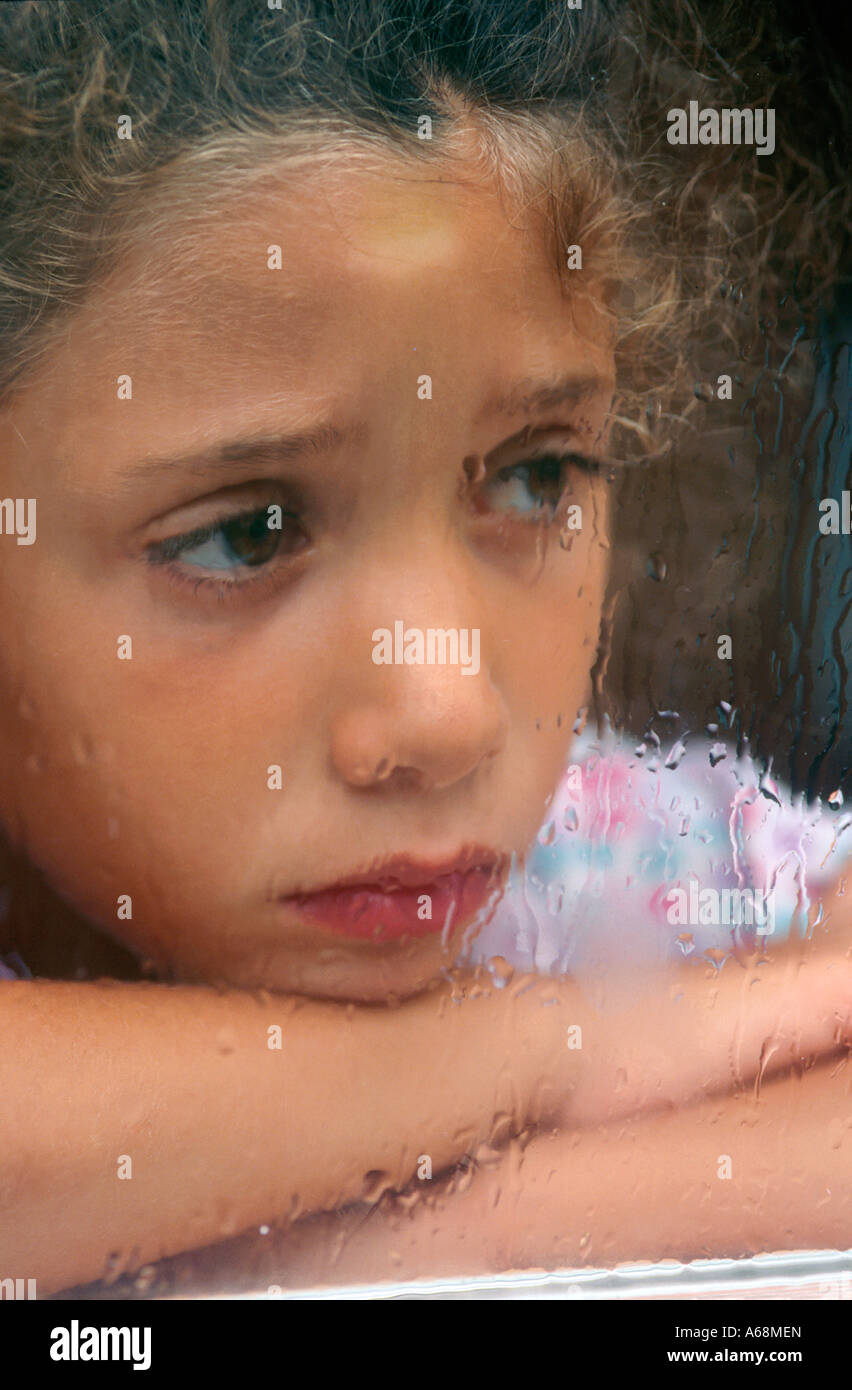 Sad girl looking out the rain streaked window Stock Photo