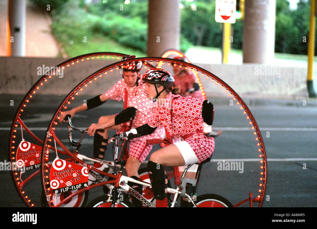 Twirling lighted summersault bicycles riding in the Aquatennial Torchlight Parade age 24. Minneapolis Minnesota USA Stock Photo