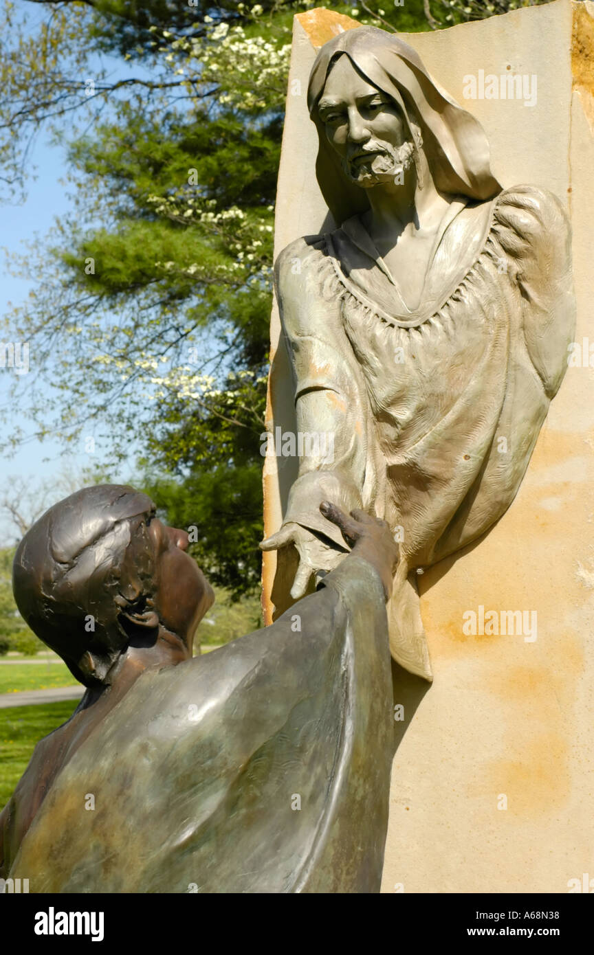Stone statue of Jesus Christ reaching his hand down to a man below