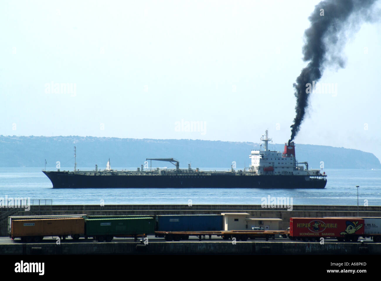 Side view cargo ship belching black smoke & soot emissions from funnel polluting local atmosphere & environment arriving Port of Palma Mallorca Spain Stock Photo