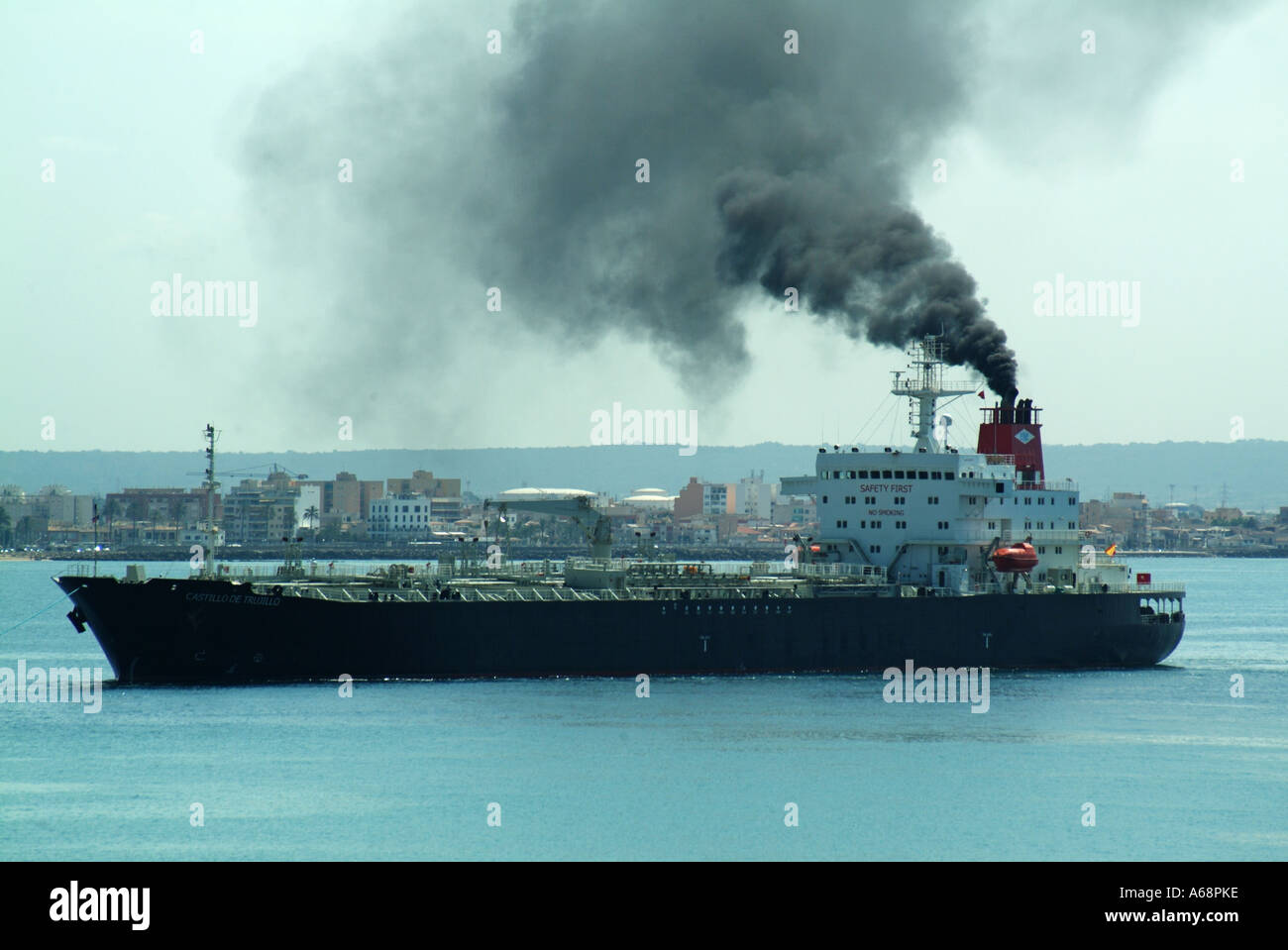Side view cargo ship belching black smoke & soot emissions from funnel polluting local atmosphere & environment arriving Port of Palma Mallorca Spain Stock Photo