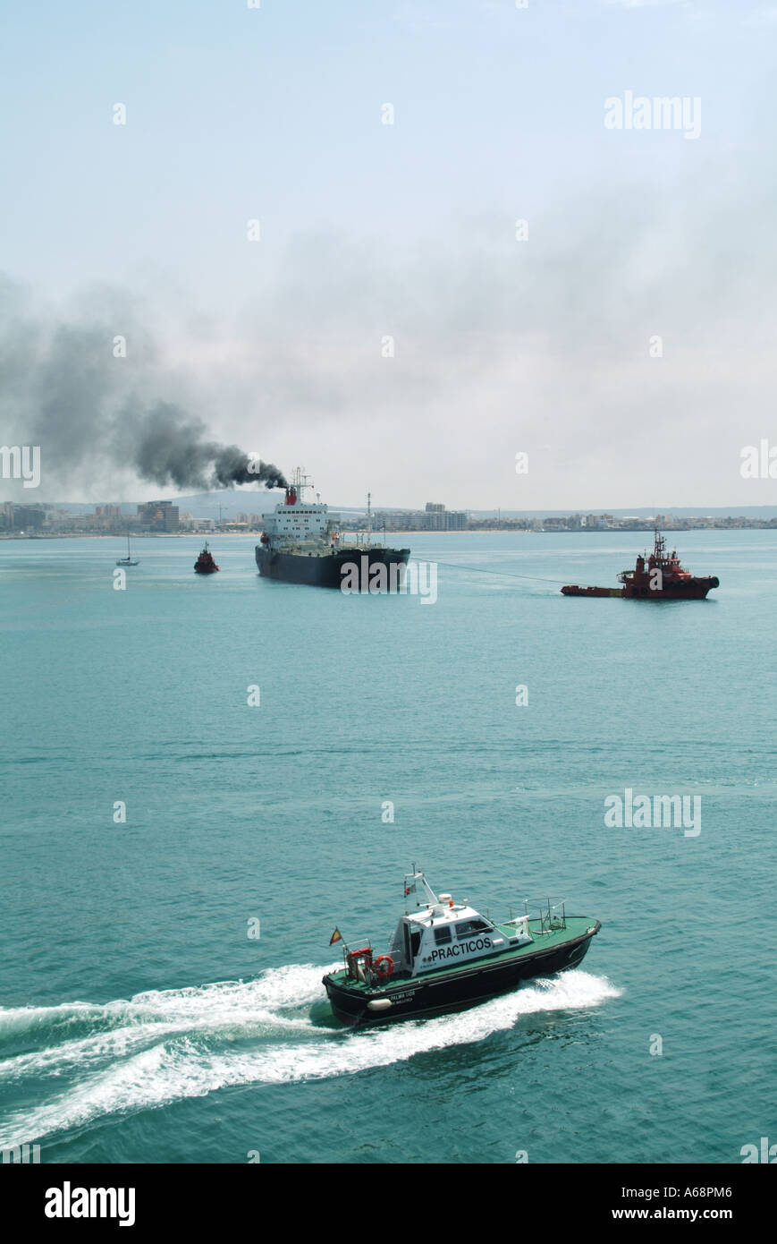 Cargo ship belching out black smoke & soot emissions from funnel polluting local atmosphere & environment arriving at Port of Palma Mallorca Spain Stock Photo