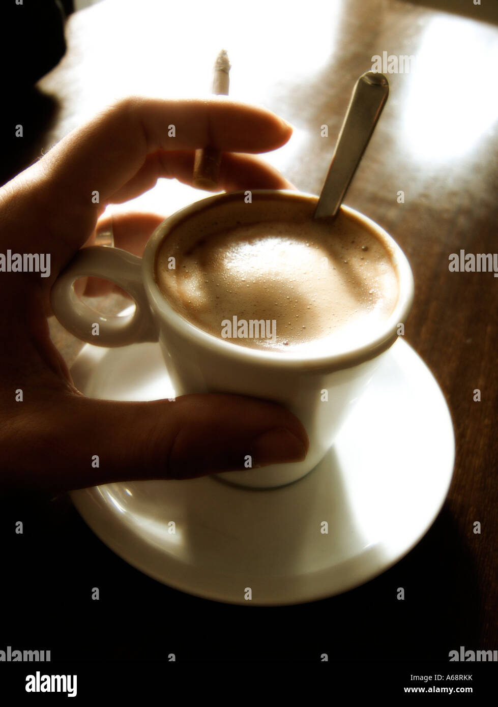 Coffee cup and hand with cigarette on a table Stock Photo