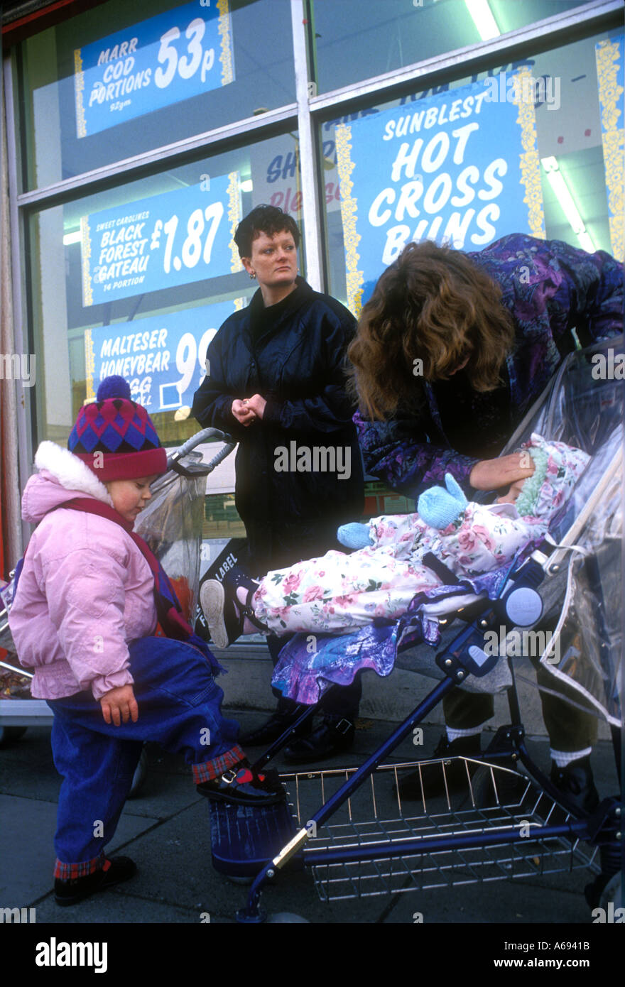 Group of mothers shopping with push chairs babies and young children. Stock Photo