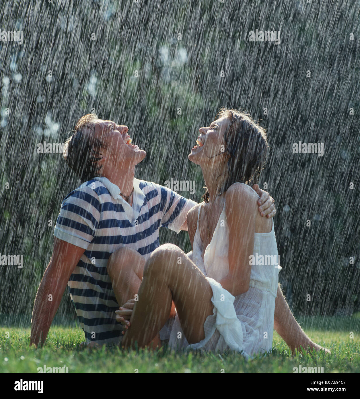Couple relaxing on lawn in rain Stock Photo