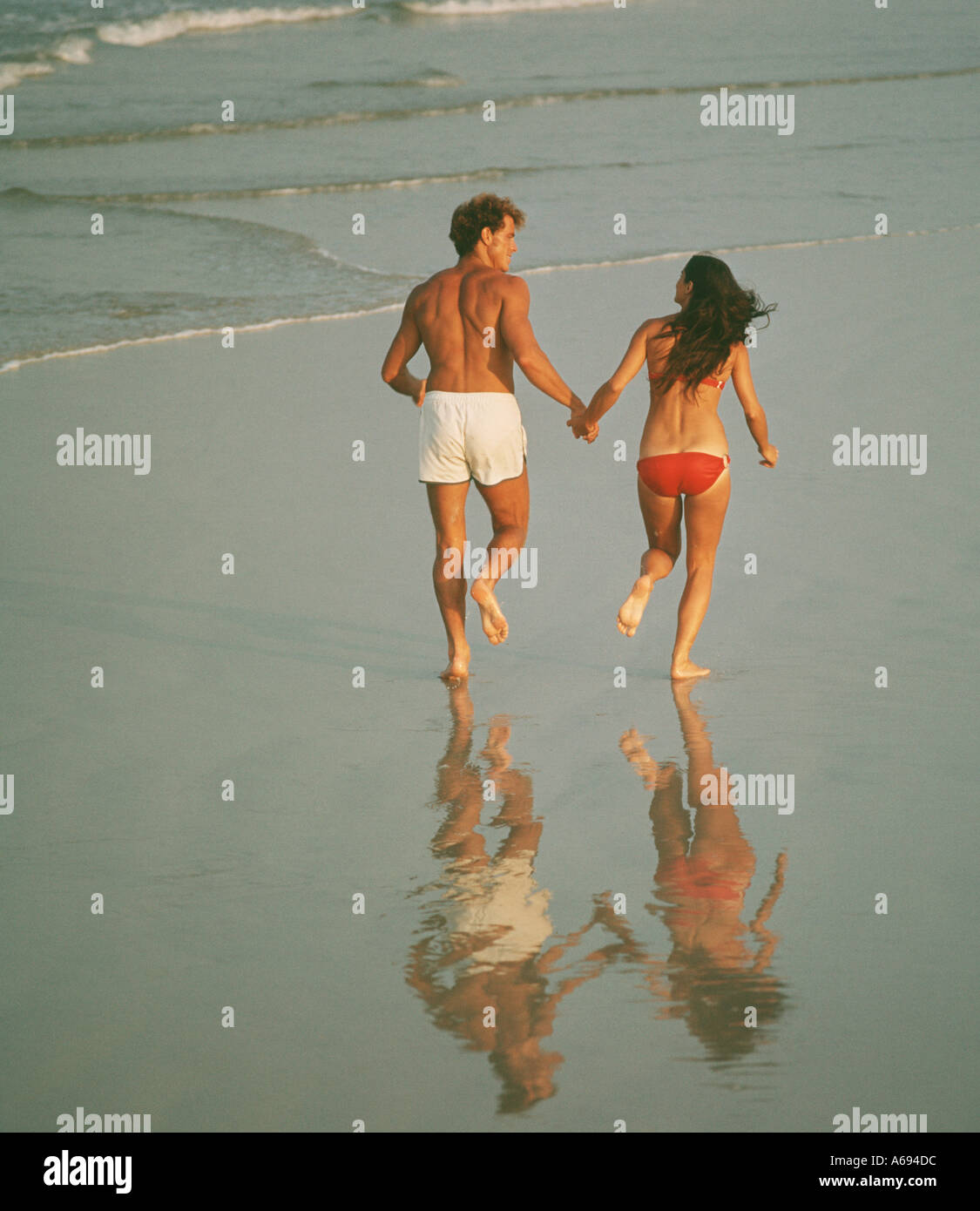 Couple running on ocean beach Stock Photo