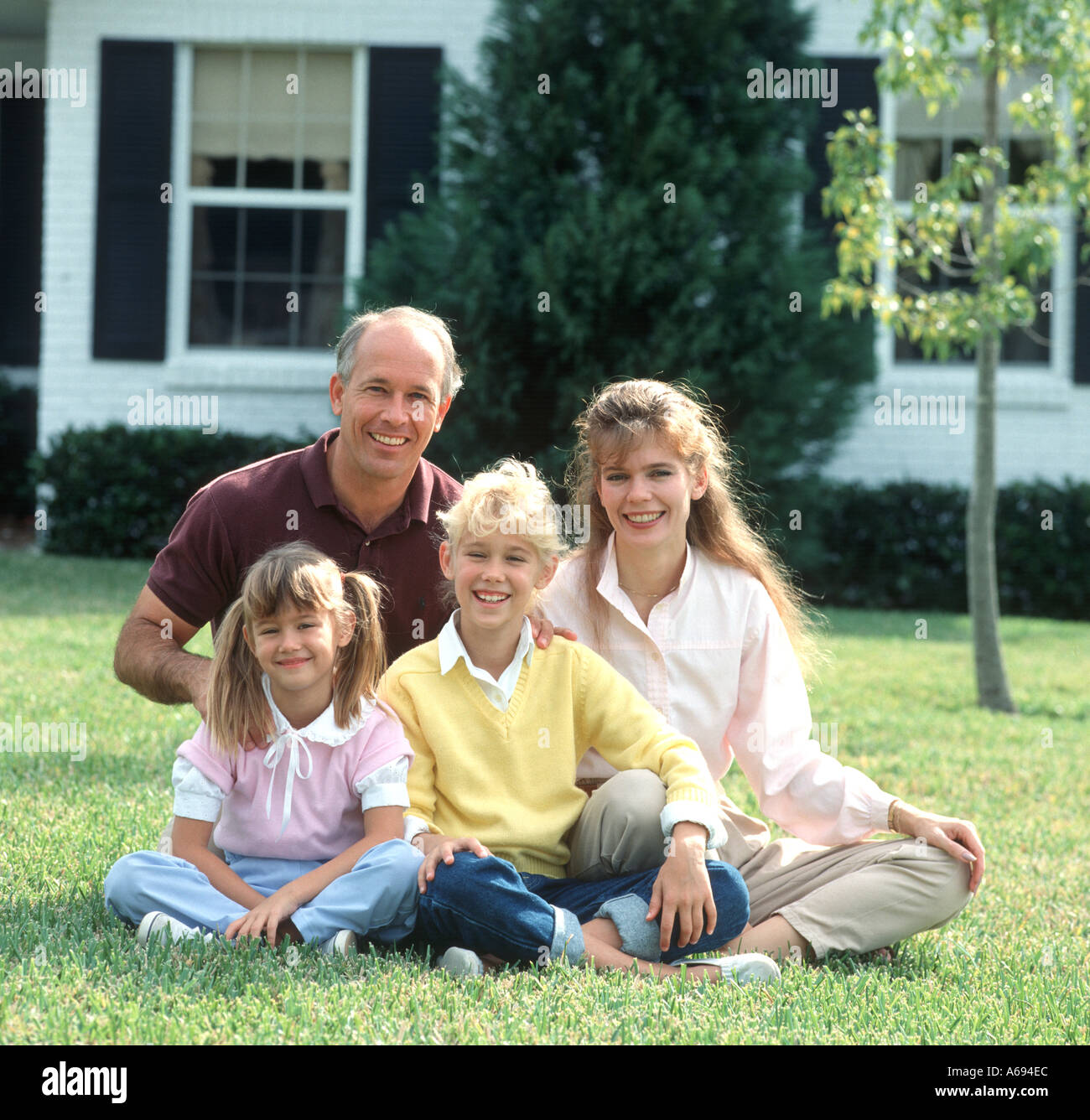 Family of four posing on lawn Stock Photo