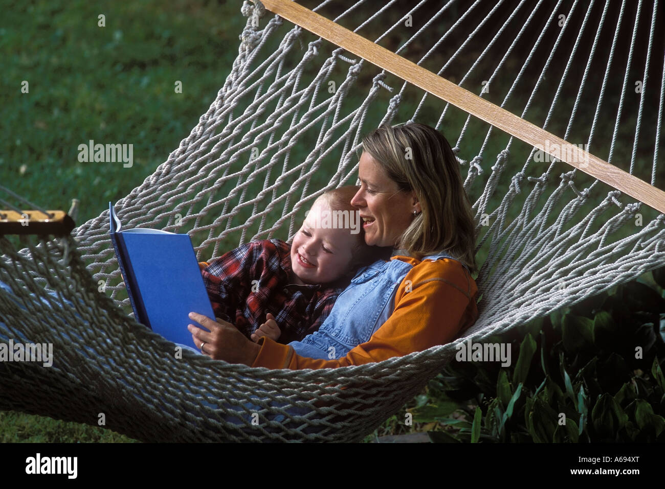 mother and son reading book in hammock Stock Photo - Alamy