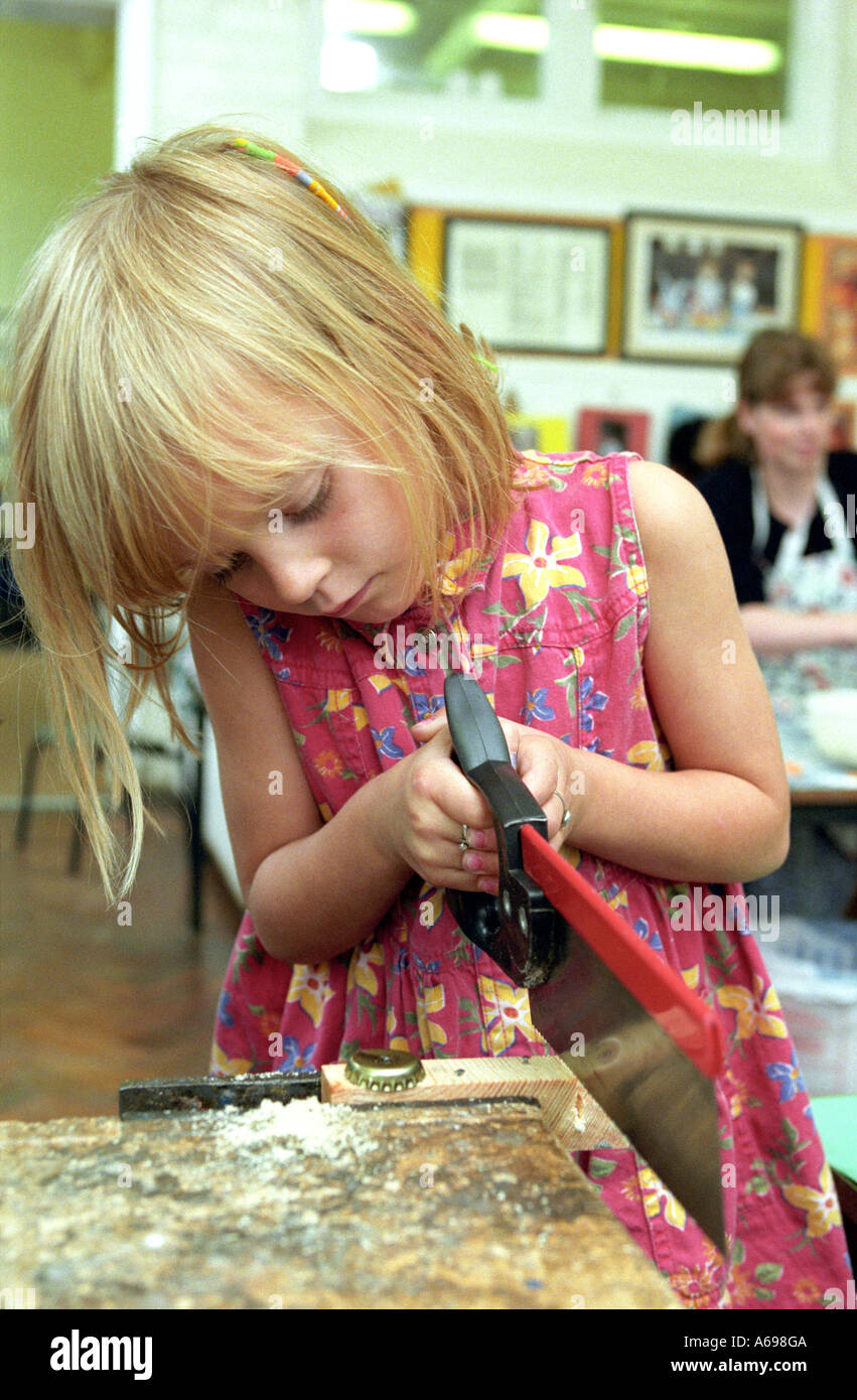 young girl learning to use a saw Stock Photo