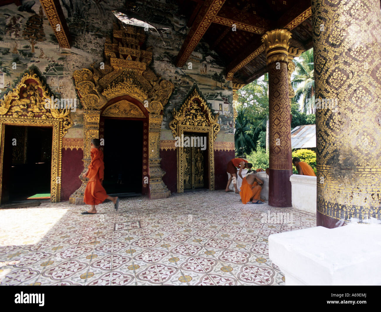 Novice buddhist monks cleaning the entrance of a temple. Luang Prabang, Laos. Stock Photo