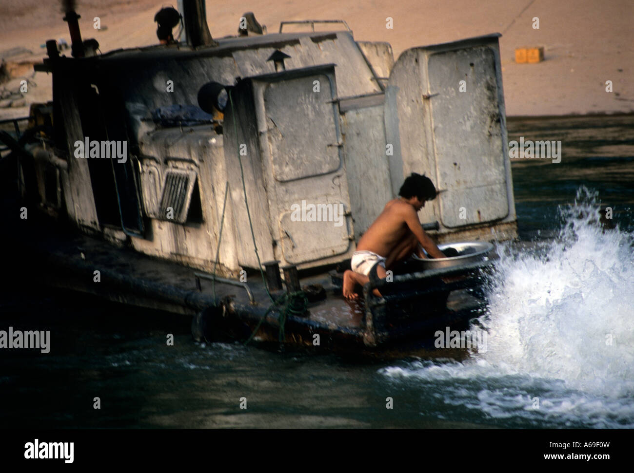 Engineer washing his clothes on the deck of a sooted ramshackle ferry on the Nam Ou river at Muang Khoua, Laos Stock Photo